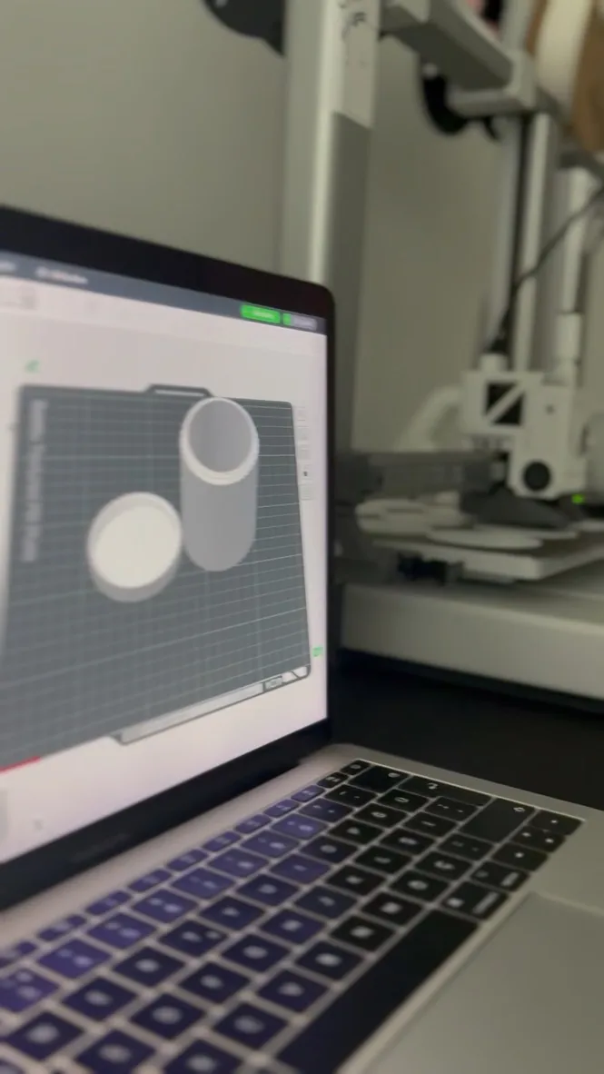 Dilimleme ekranı açık dizüstü bilgisayar, arkada 3D yazıcılar